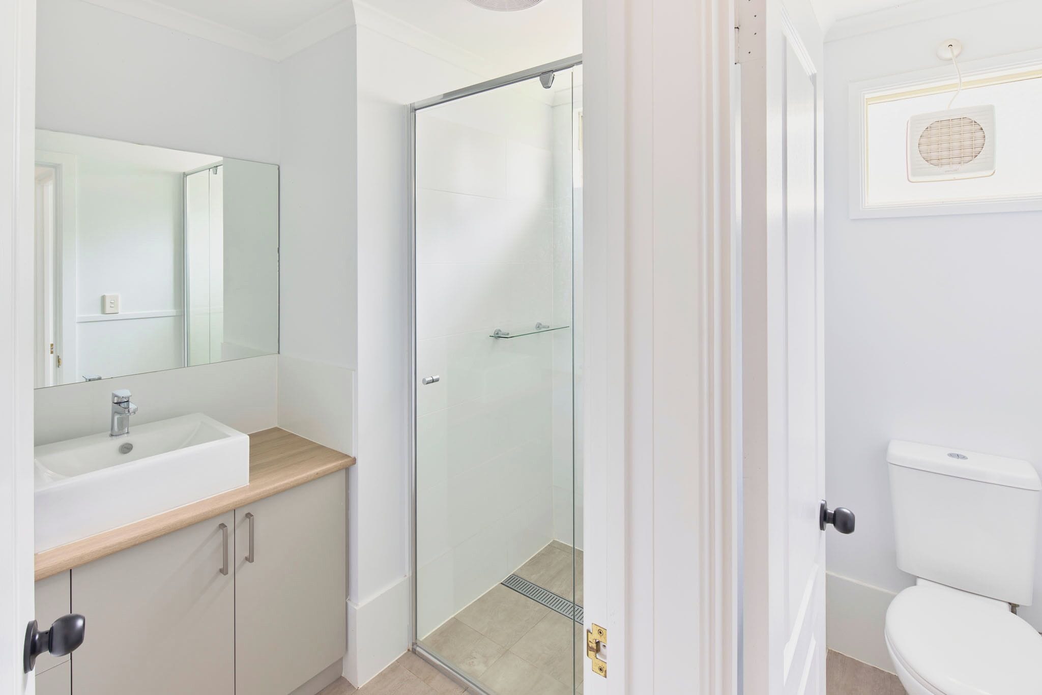 Une salle de bain moderne avec une douche à parois de verre, un lavabo blanc et des toilettes.