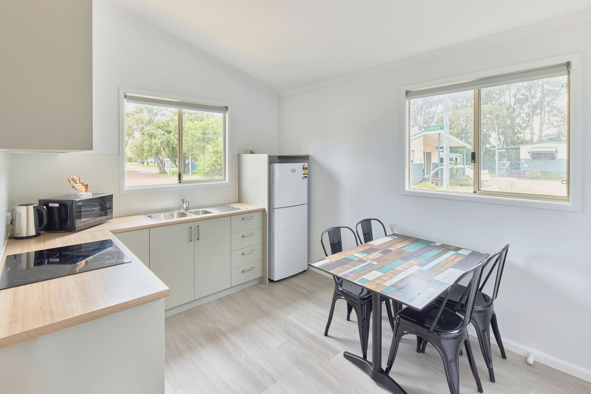 A modern kitchen with a built-in microwave, a refrigerator, and a dining area with a wooden table and chairs.