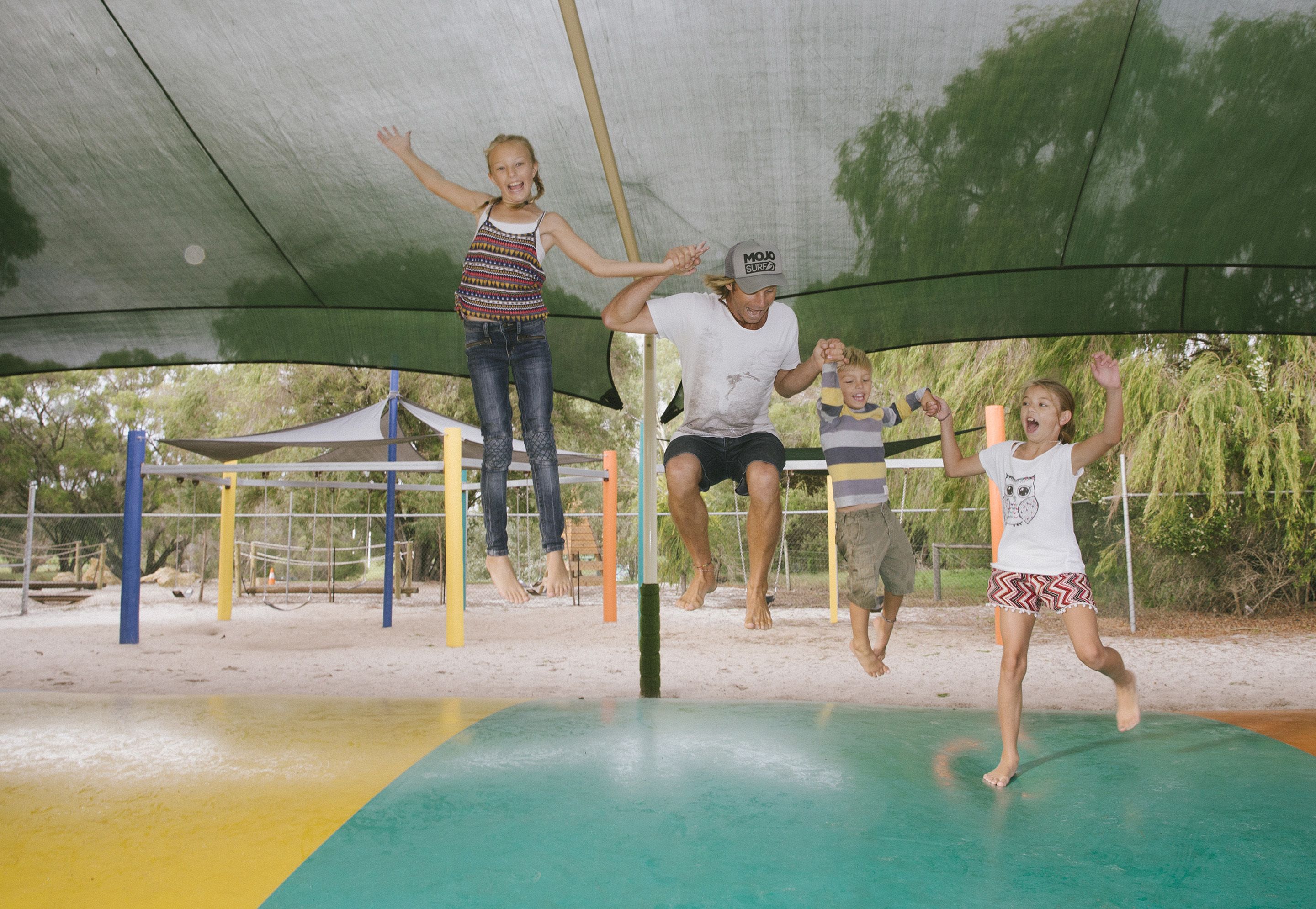 A covered outdoor area with a trampoline and a netted play structure.