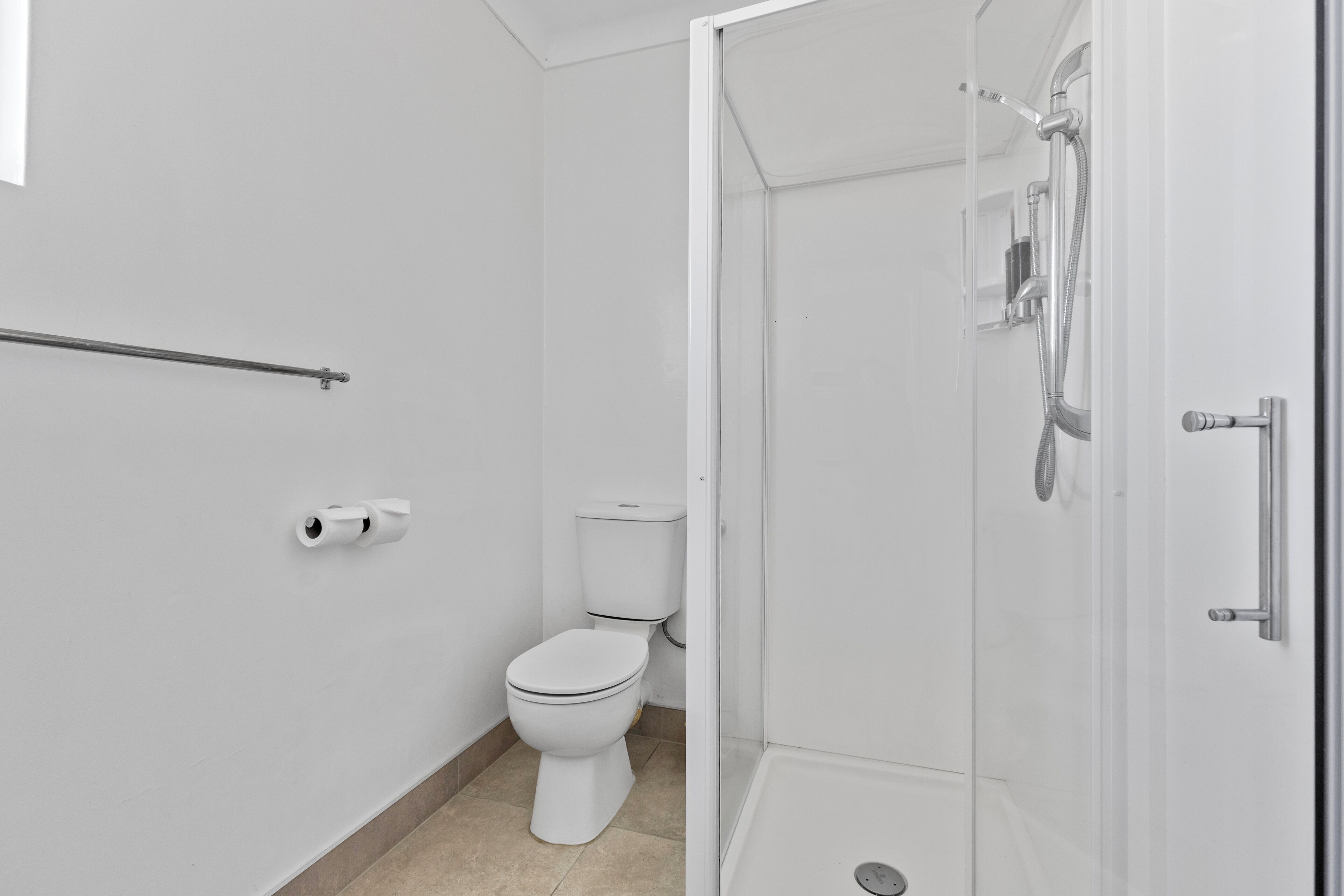 Ein modernes Badezimmer mit Toilette, Duschkabine und Haltestange.