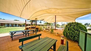 An outdoor patio area with picnic tables and a large canopy providing shade.