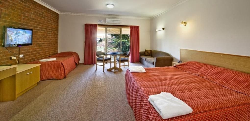 Una habitación de hotel con una cama individual, un escritorio, una silla, un sofá y un televisor.