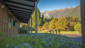 A covered outdoor area with a view of mountains and a picnic table. - Rainforest Motel (Fox Glacier)
