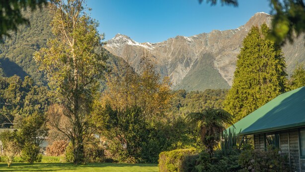 A mountain landscape with a cabin in the foreground. - Rainforest Motel (Fox Glacier)
