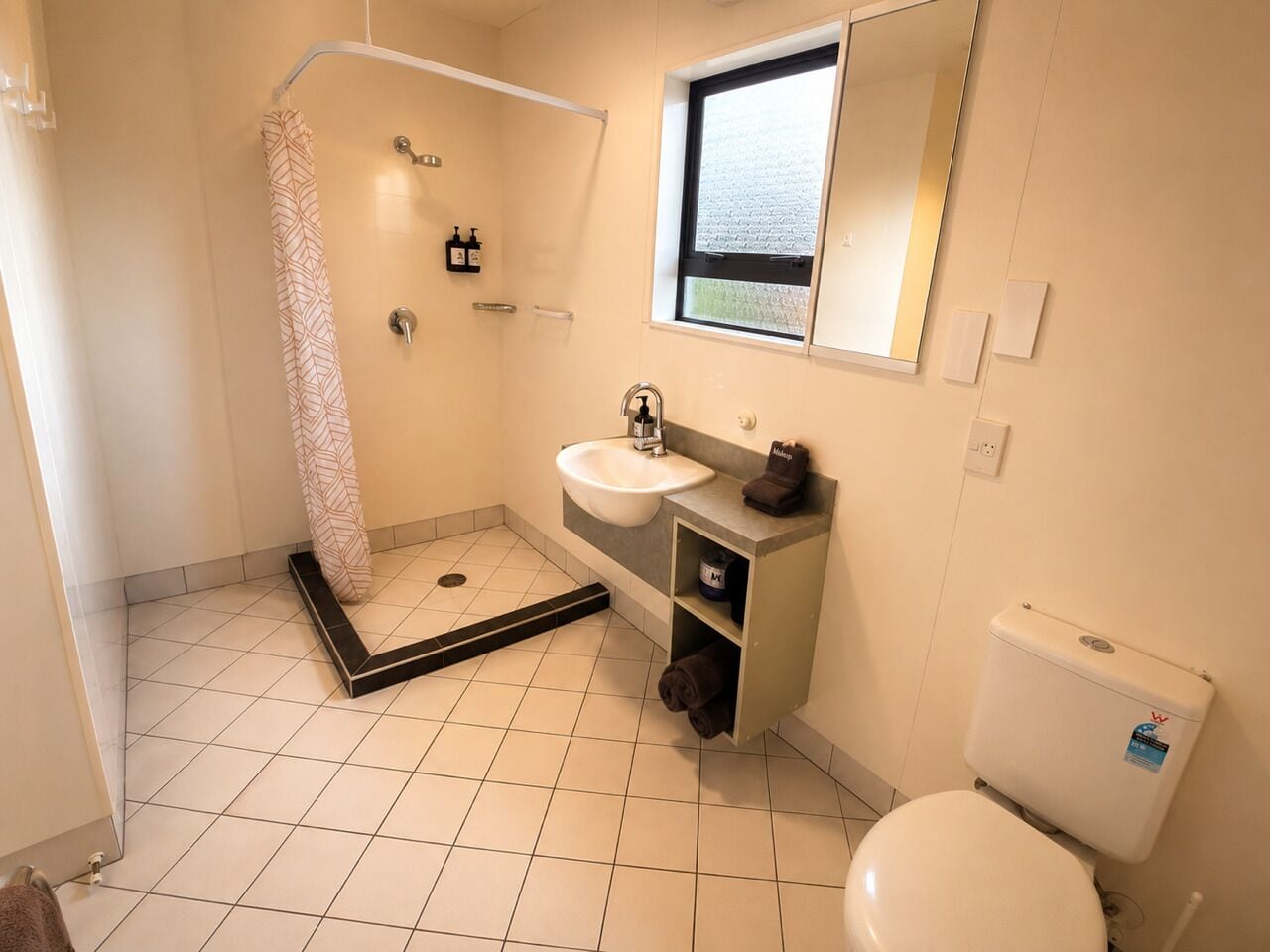 A bathroom with a shower, sink, and toilet.
