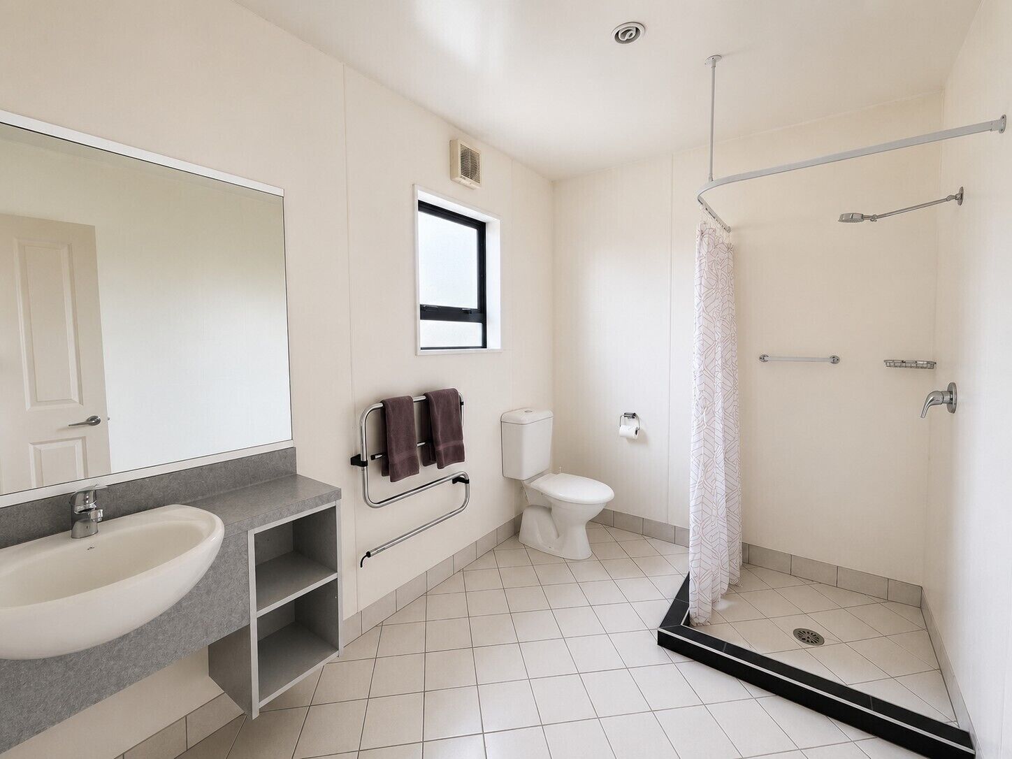 A modern bathroom with a sink, mirror, toilet, and shower.