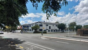 A building with a flat roof, large windows, and a sign for a motor lodge. - Abode Motel (Palmerston North)