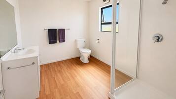 A bathroom with a shower, toilet, sink, and a window.
