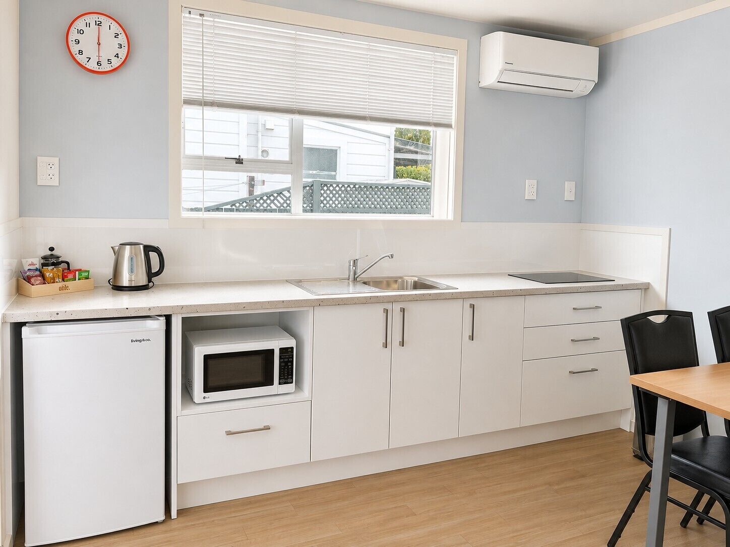 Een kleine keuken met een magnetron, spoelbak en een koelkast.