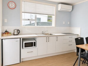 Una kitchenette compacta con microondas, pileta y heladera pequeña.