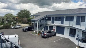 A multi-story building with a parking area, a covered staircase, and a balcony with railings. - Abode Motel (Palmerston North)