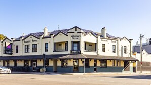 A two-story Albion Hotel with a classic architectural style, featuring a prominent sign and a parking area at the rear. - The Albion Hotel (Wickham)