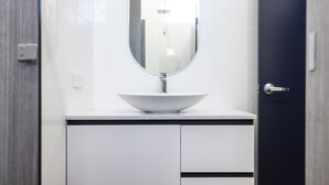 A modern bathroom with a white sink, a mirror, and a door. - The Albion Hotel (Wickham)