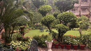 A lush garden with various plants and a bench. - The Estate Villa (New Delhi)