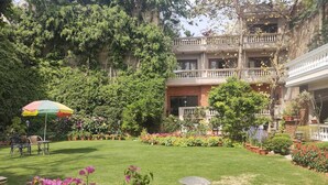 A well-maintained garden with a lawn, potted plants, and a colorful umbrella. - The Estate Villa (New Delhi)