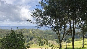 A patio area with a view of a lush green landscape and distant hills. - Top Cottage at Maleny (Wootha)