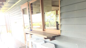 A covered porch with wooden benches and a window overlooking a garden. - Top Cottage at Maleny (Wootha)