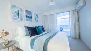 Ett hotellrum med en stor säng, ett runt bord och utsikt över himlen genom fönstret.