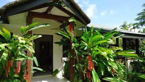 Una casa tropical con techo de paja, rodeada de exuberante vegetación y plantas de plátano.