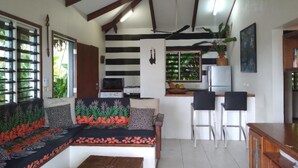 Una sala de estar acogedora con sofá, una mesa de centro y una zona de cocina equipada con refrigerador, estufa y sillas.