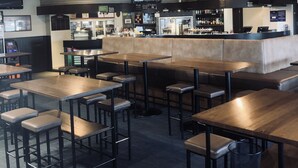 A restaurant with high ceilings, exposed beams, and a bar area. Tables and stools are arranged for dining. - Tinwald Motels (Ashburton)