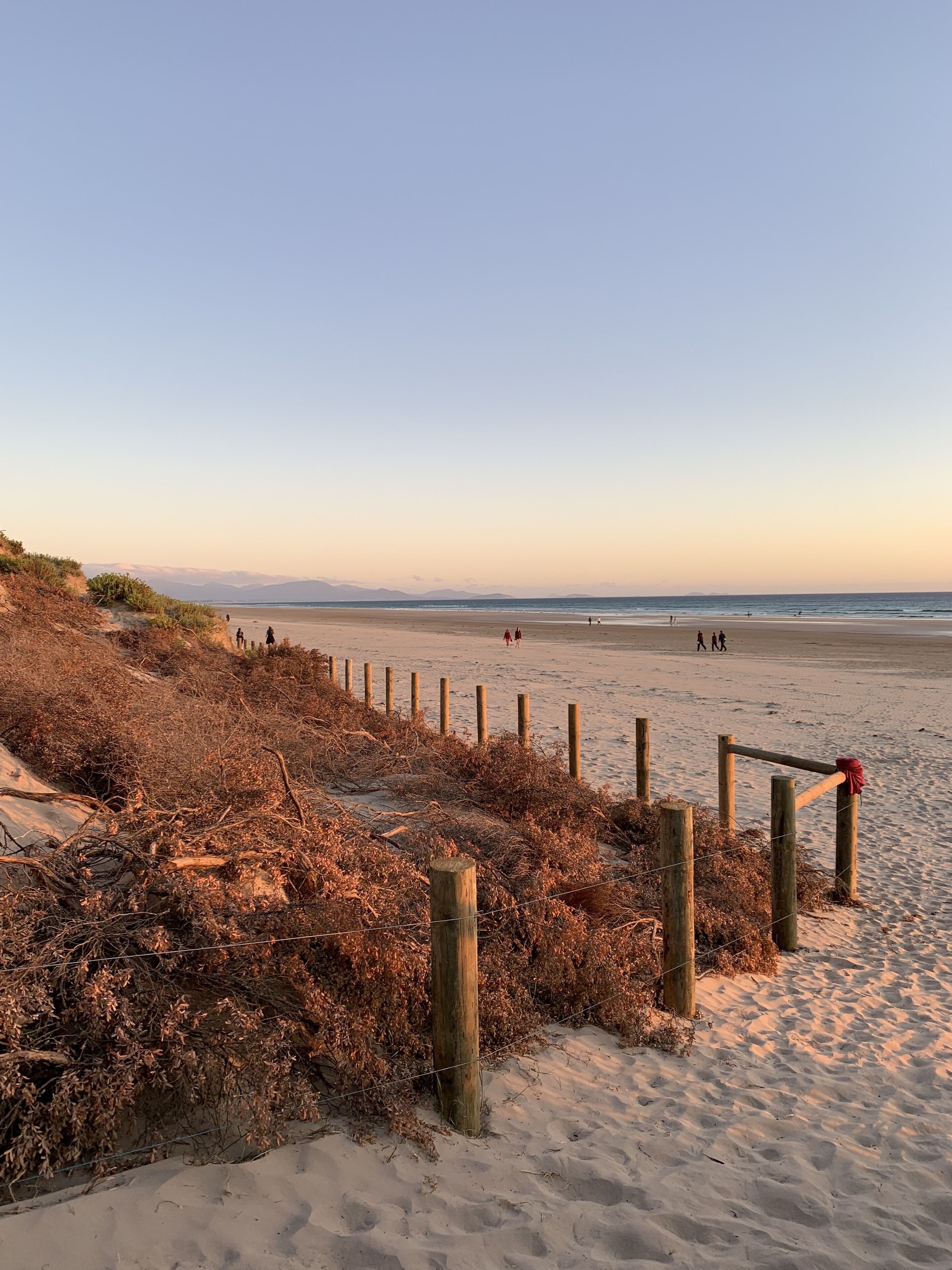 A beach with a wooden fence and a clear sky.