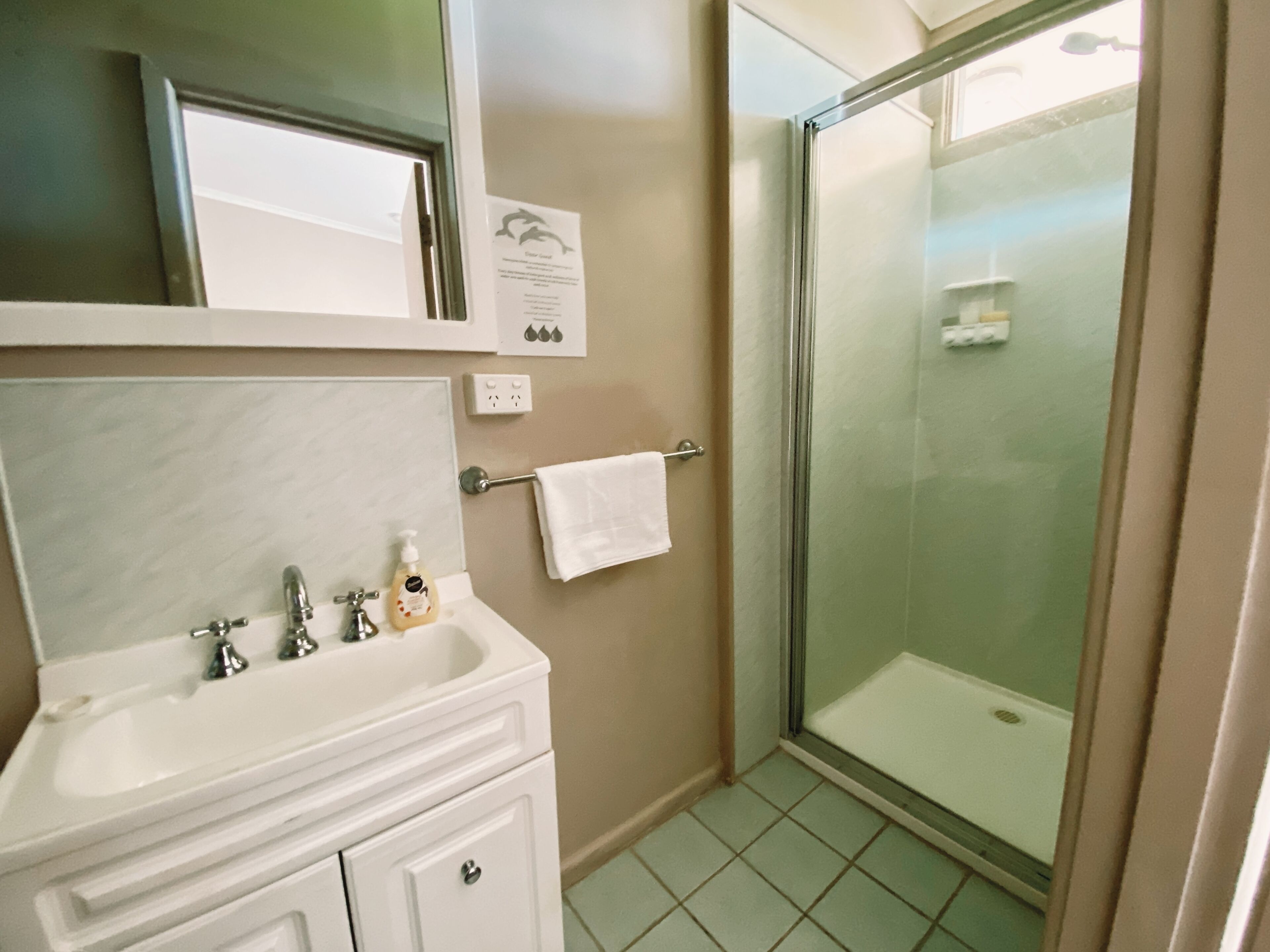 A bathroom with a white sink, mirror, and glass shower enclosure.