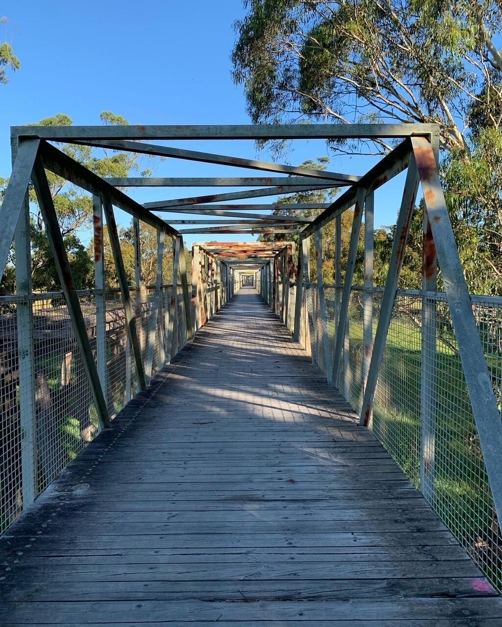 A wooden pedestrian bridge with metal railings and a metal roof structure.