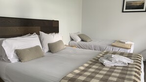 A hotel room with two beds, each with white bedding and beige pillows. There is a checkered throw blanket on the larger bed. - Meeniyan Motel (Meeniyan)