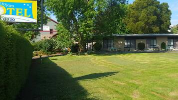 A motel with a signboard, a lawn, and a building with multiple rooms.