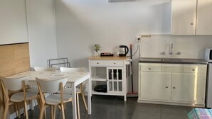 A compact hotel room with a bed, a small desk, a kitchenette, and a window. - Meeniyan Motel (Meeniyan)