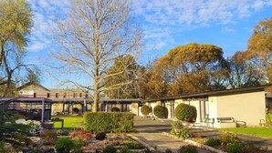 A courtyard with a building, a covered seating area, and a variety of plants. - Meeniyan Motel (Meeniyan)
