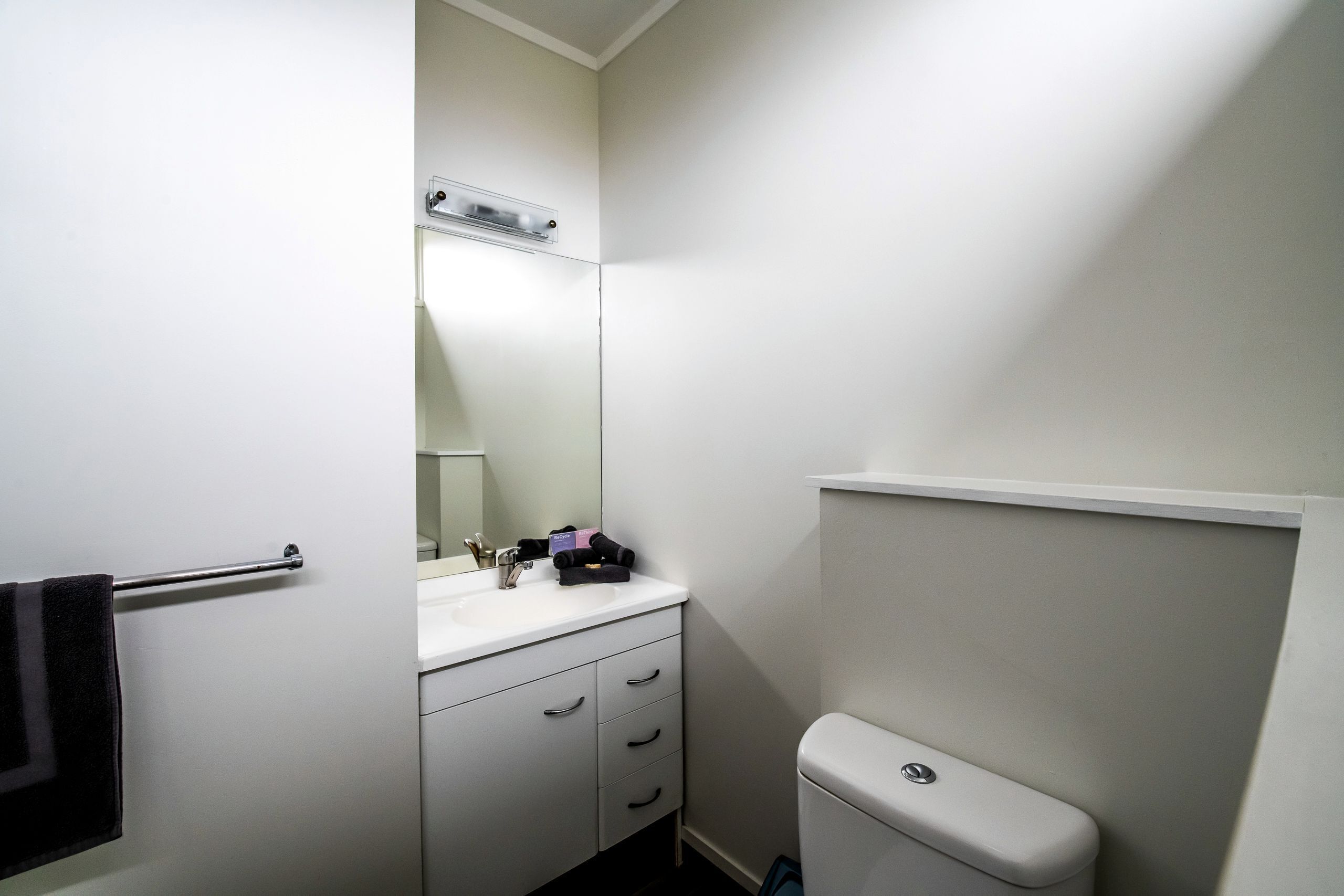 A small, clean bathroom with a white sink, mirror, and toilet.