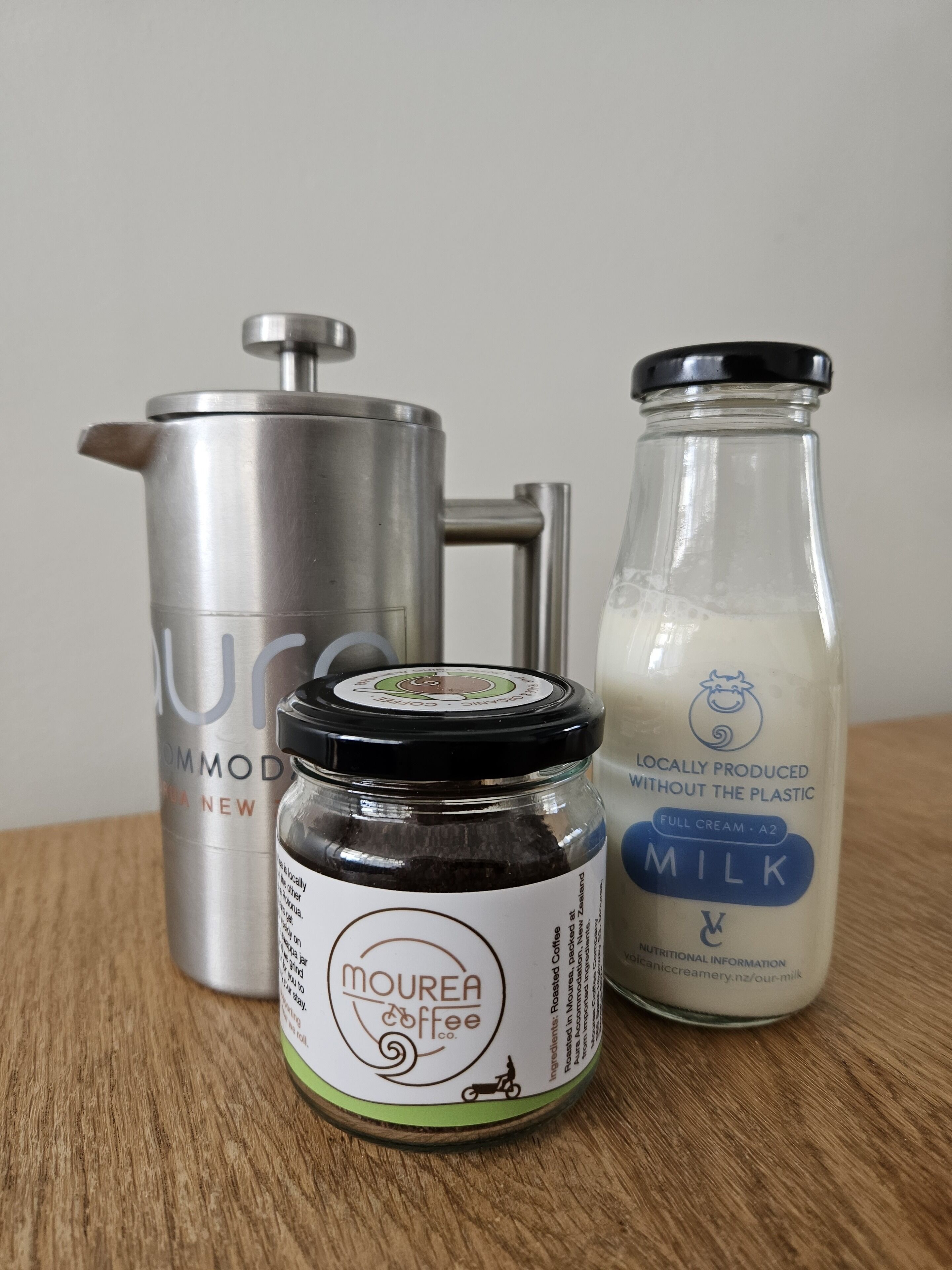 Une machine à café, un biberon et un pot de crème à café sur une surface en bois.