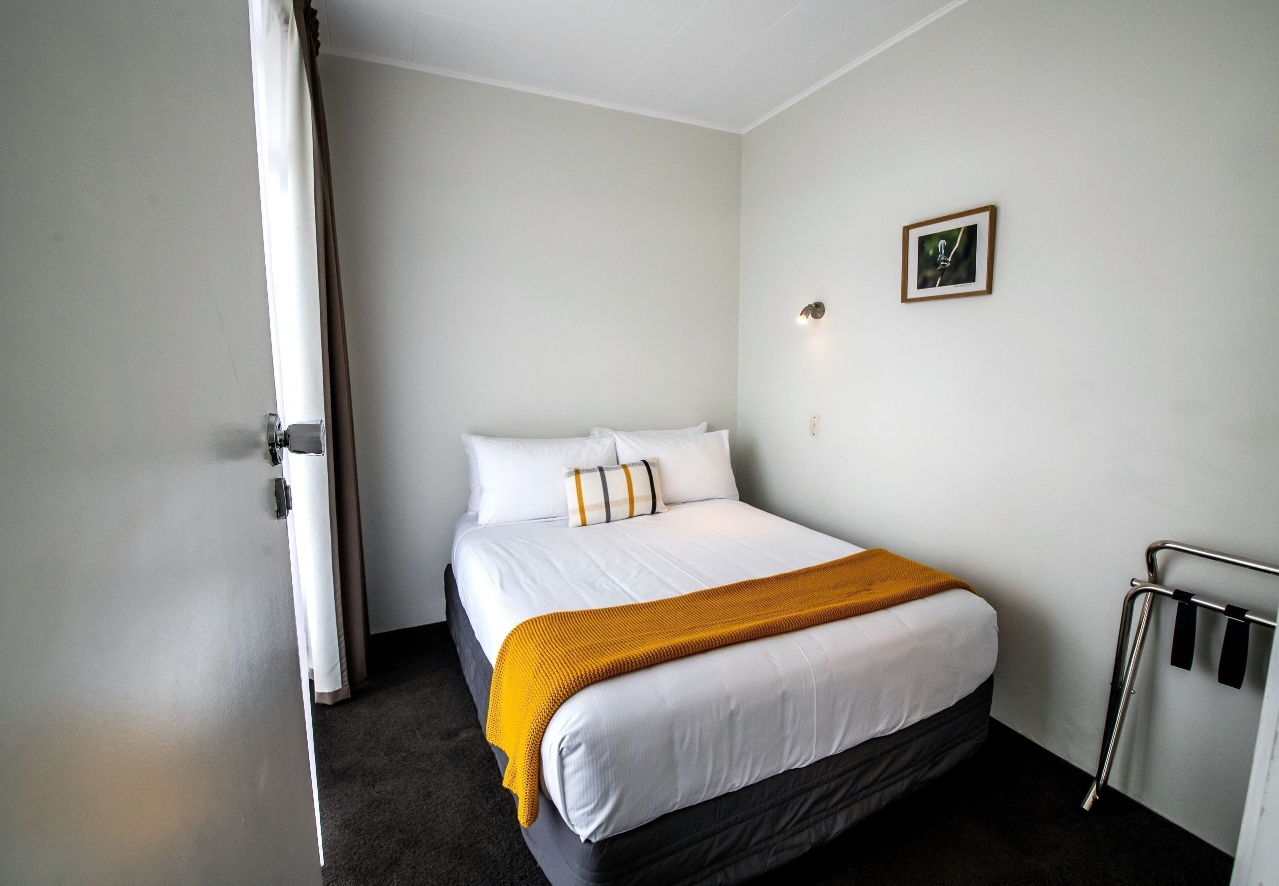 Ein Hotelzimmer mit einem Bett, einer weißen Wand, einem Bild und einem Heizkörper.
