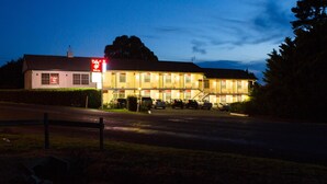 A two-story motel with a red sign, multiple windows, and a parking lot. - Colonial Lodge Motor Inn Yass (Yass)