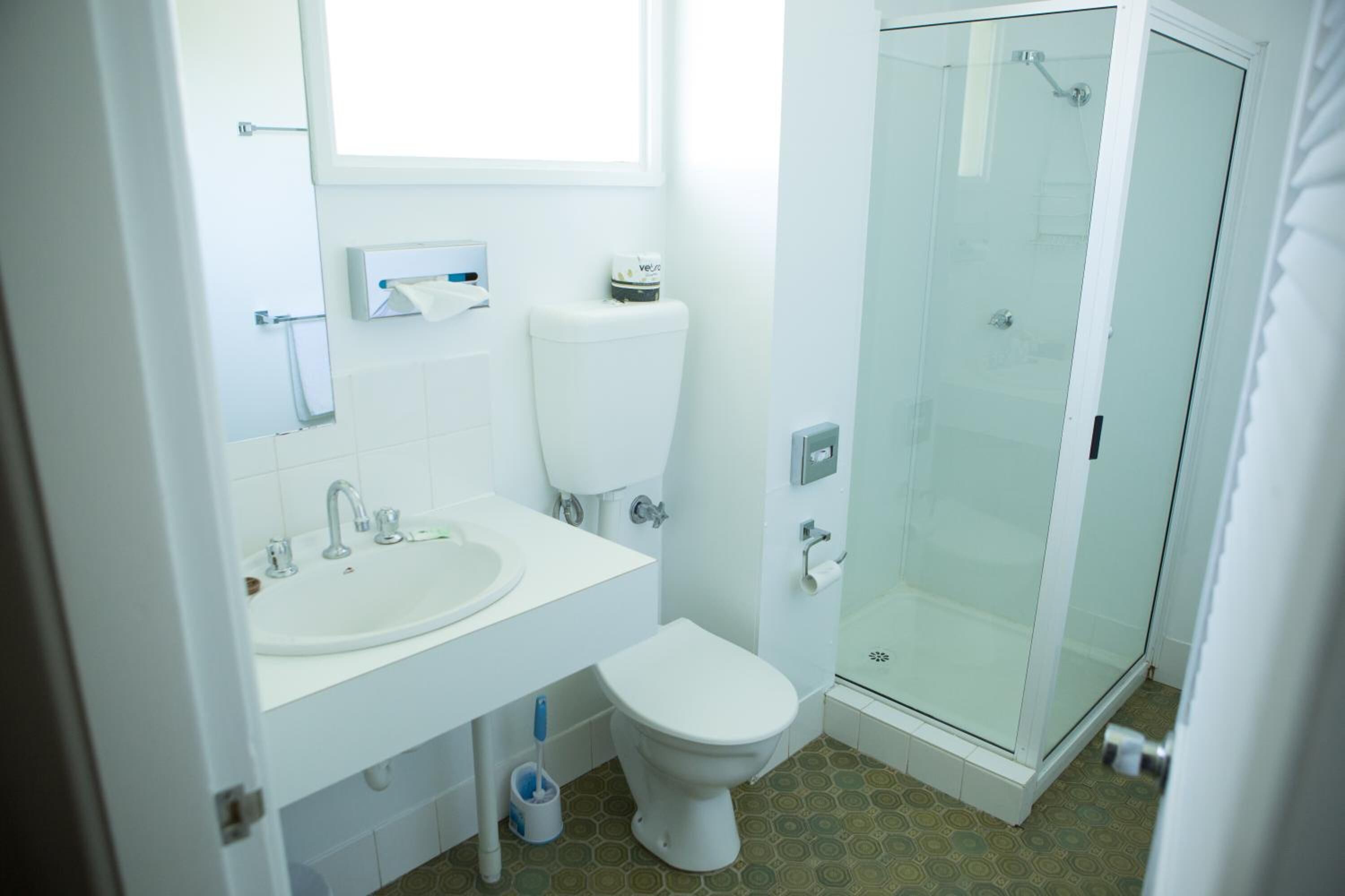 Un baño con inodoro, lavamanos y ducha envuelta en vidrio.