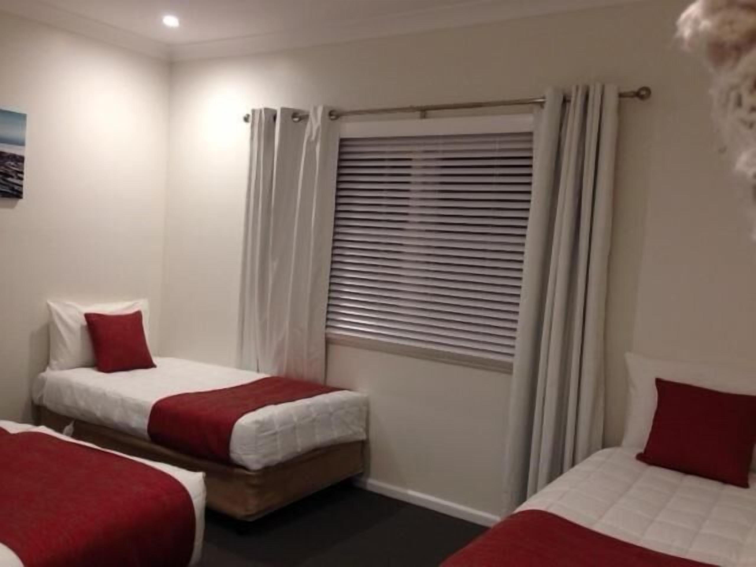 Een hotelkamer met twee bedden, elk voorzien van een rood kussen en witte beddengoed.