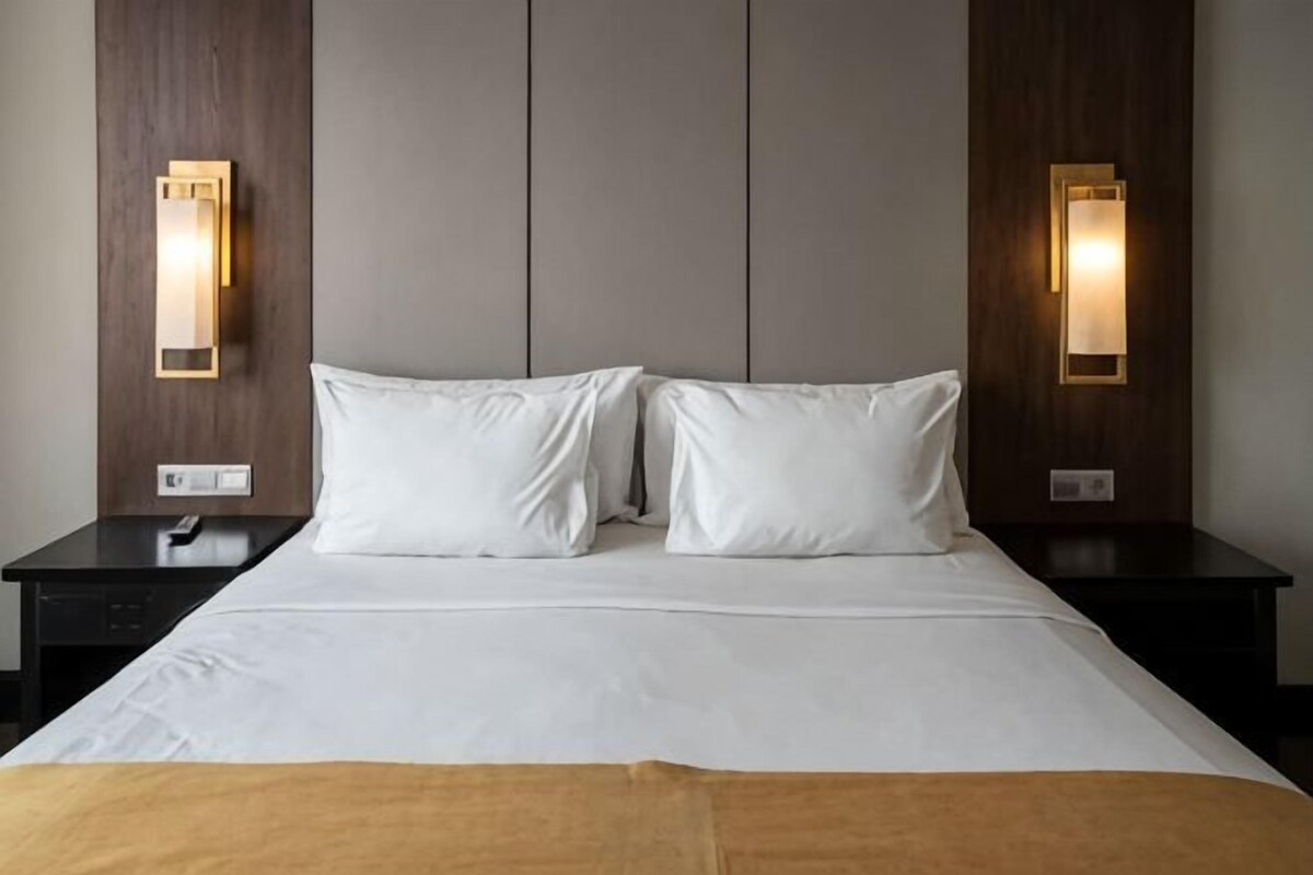 Ein Hotelzimmer mit einem großen Bett, zwei Nachttischen und Wandleuchten.