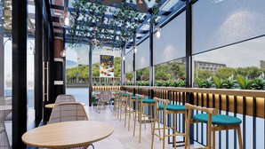 Un café moderno con mesas y sillas de madera, un ventanal con plantas y una pizarra con el menú.