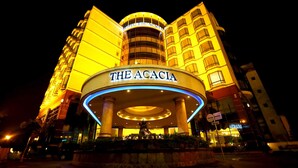 Un hotel con una entrada circular destacada y el nombre “The Acacia” exhibido en la parte superior.