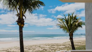 A beach view from a balcony with palm trees and a wooden table. - Surfers Horizons Resort (Palm Beach)
