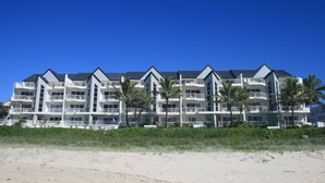 A beachfront hotel with multiple balconies, palm trees, and a clear blue sky. - Surfers Horizons Resort (Palm Beach)