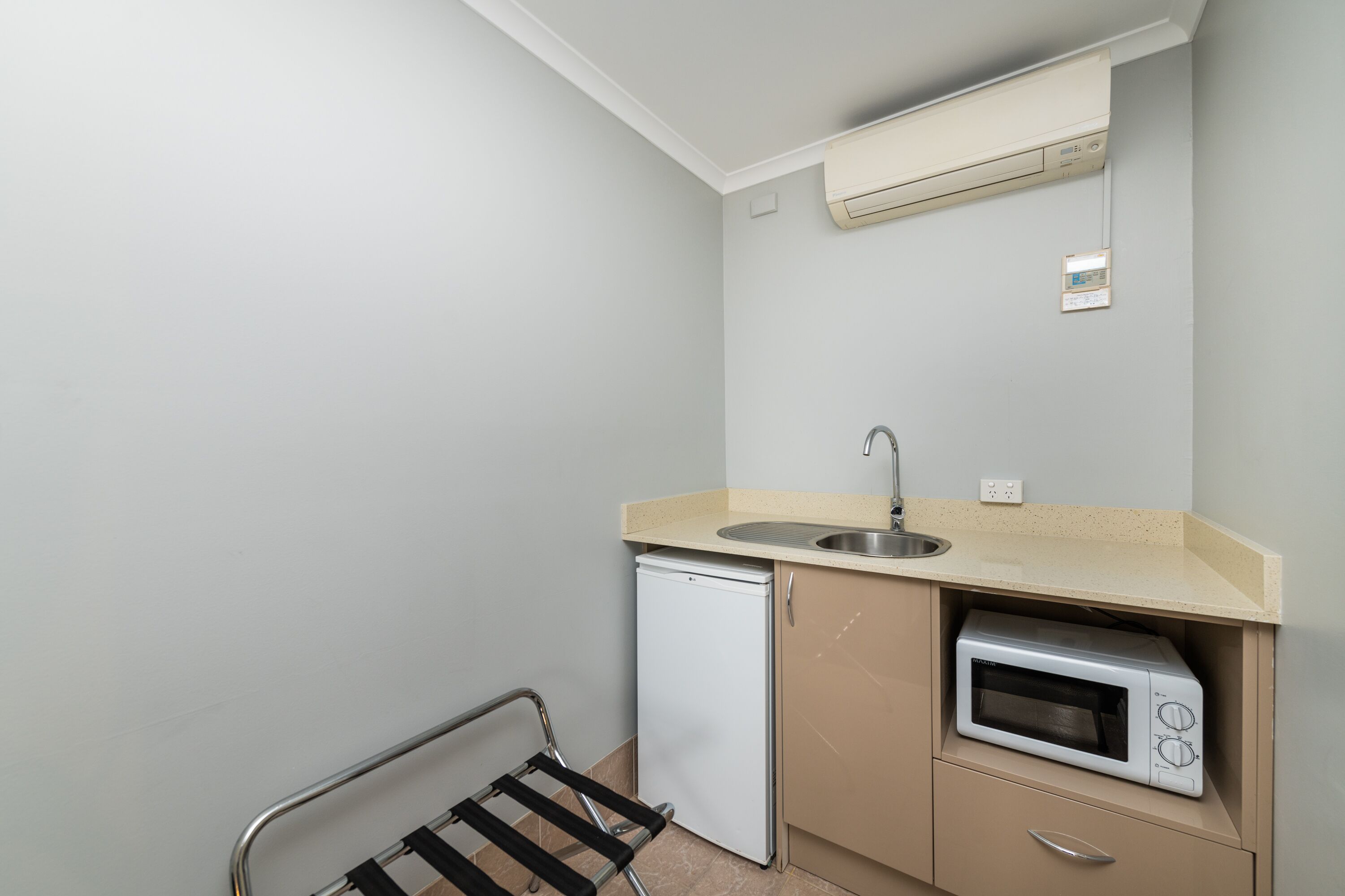A compact kitchenette with a built-in microwave, a small refrigerator, and a sink.