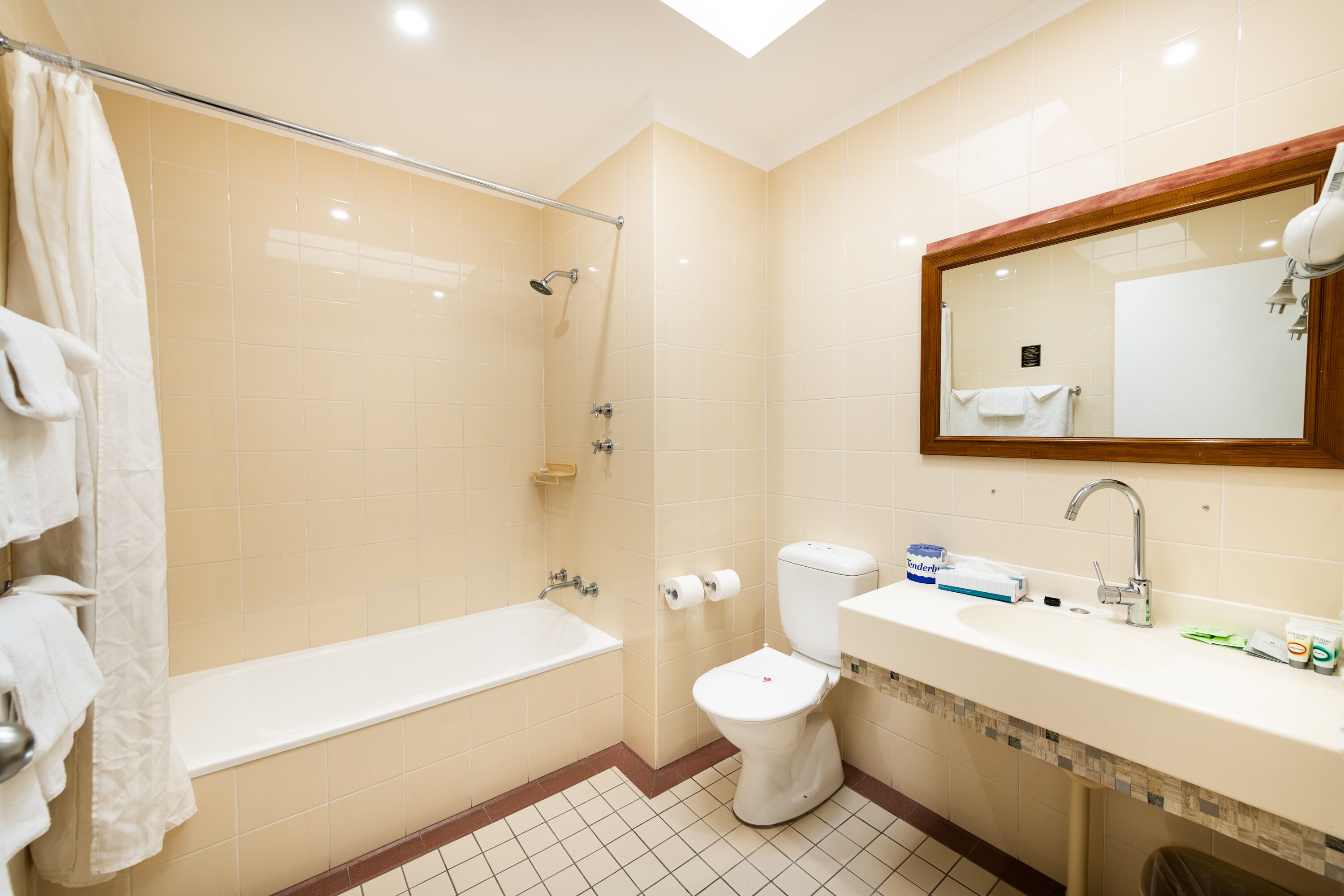 A bathroom with a bathtub, toilet, sink, and a mirror.