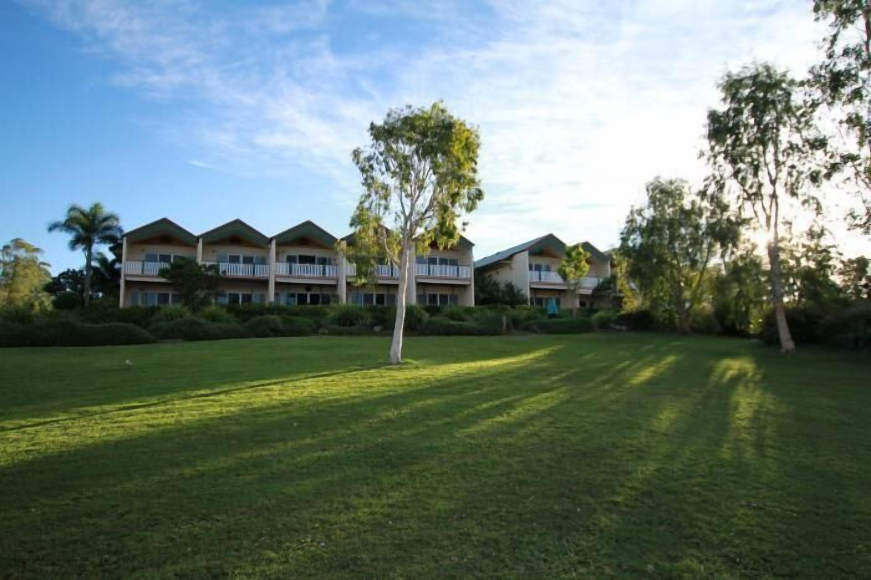 A hotel with multiple buildings, a well-maintained lawn, and trees.