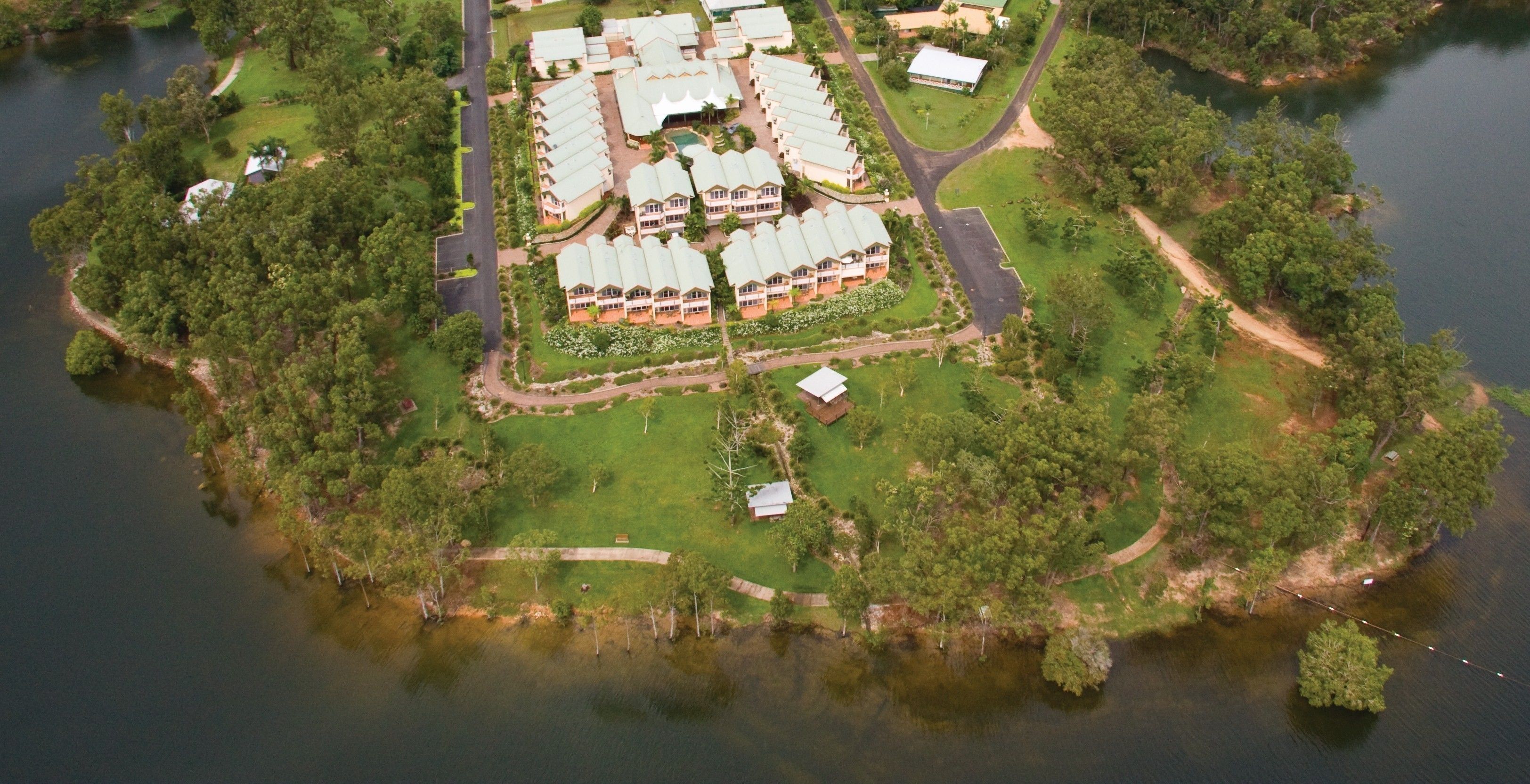 Luchtbeeld van een resort met meerdere gebouwen, een centrale binnenplaats en omliggend groen.
