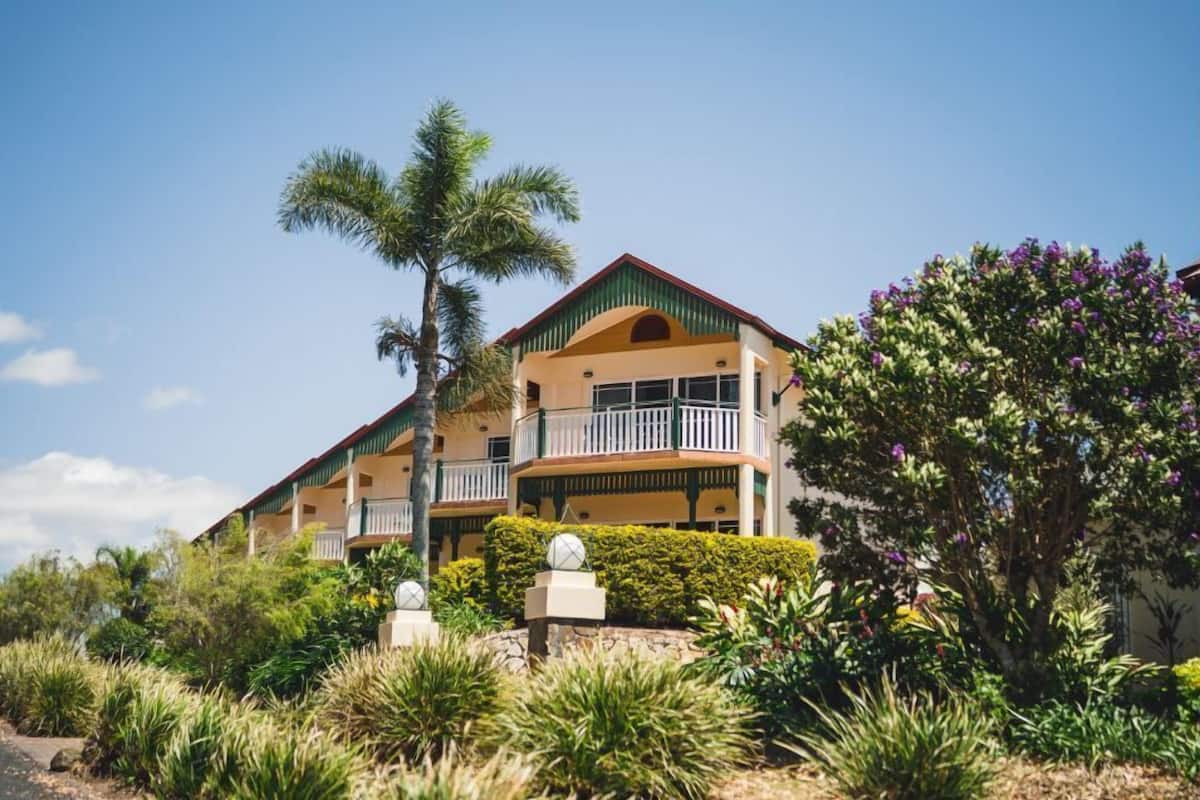 Un hôtel à plusieurs étages doté de balcons, entouré d’une végétation tropicale.