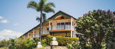 A multi-story hotel with balconies, surrounded by tropical vegetation.