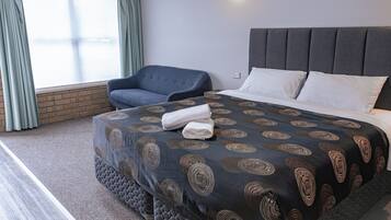 A hotel room with a bed, a chair, and a window with curtains.